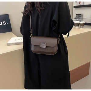 Detail of dark brown shoulder bag with matte leather texture and gold hardware clasp