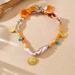 Detail of silk scarf necklace with golden sun face and turquoise heart charms