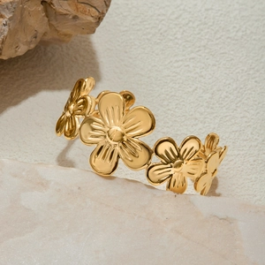 Detail of 18K gold-plated stainless steel flower cuff bracelet on a minimalist rock background