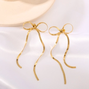 Golden stainless steel bow tassel hoop earrings displayed on white silk background