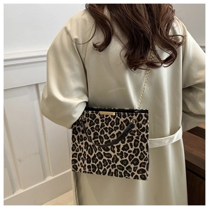 Leopard print crossbody bag with gold chain strap shown on beige trench coat