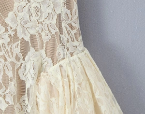 Detailed macro view of white floral lace fabric and pleated hemline with soft inner lining