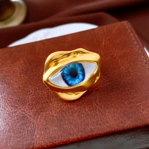 Close-up of golden irregular ring featuring a blue evil eye on vintage leather