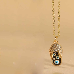 Macro detail of gold flip-flop pendant with inlaid zircons and enamel evil eye charms