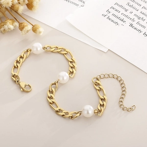 Detail of golden Figaro chain bracelet with three white pearls and lobster clasp closure