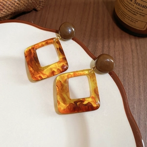 Close-up of vintage amber resin earrings on a decorative plate with warm lighting