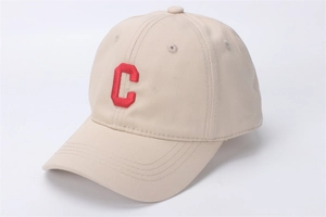 Detail van beige katoenen baseballpet met rode geborduurde letter C en nette afwerking