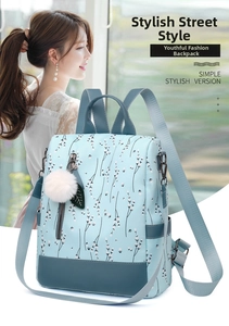 Detail of light blue floral oxford backpack showing plush ball charm and adjustable strap