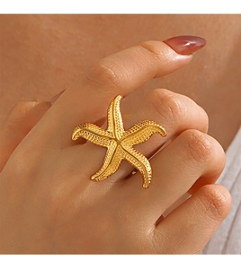Close-up of a golden starfish open ring worn on a finger for a trendy beach style look