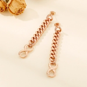 Detail of rose gold Cuban chain earrings with infinity symbol on beige background