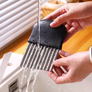 Stainless steel crinkle potato cutter with black handle being rinsed under water