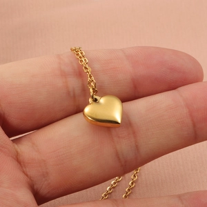 Collier à pendentif cœur doré poli sur le doigt pour montrer la taille et la texture