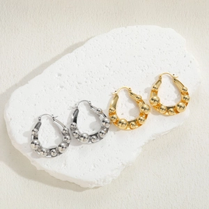 Minimalist copper bead hoop earrings in gold and silver finish on a textured stone