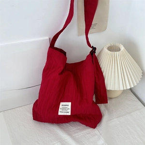 Detail showing the red pleated canvas fabric texture and large capacity of the shoulder bag