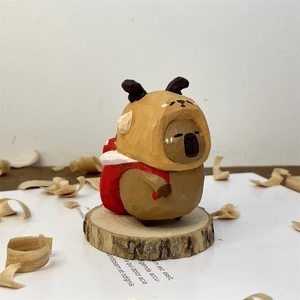Detail of hand-carved wooden capybara figurine with reindeer hat and red pack
