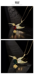 Detailed close-up of hummingbird pendants with vibrant red and green gems on black rock