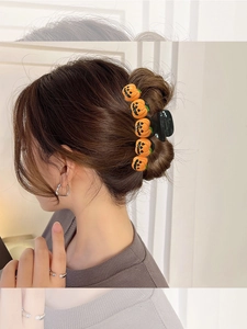 Side view of hair claw clip with orange pumpkin wizard hats on a female model