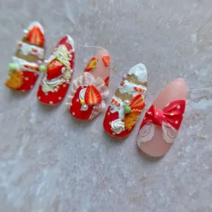 Macro shot of 3D strawberry and cream nail art stickers with lace and pearl details