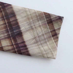 Close-up of vintage brown plaid mesh fabric with fine sheer texture and knit details