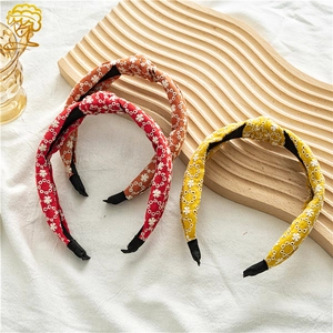 Three knot headbands in red, orange, and yellow with delicate white flower embroidery
