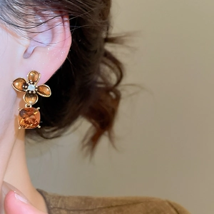 Detail of amber vintage flower earrings with faceted zircon drop on a model ear