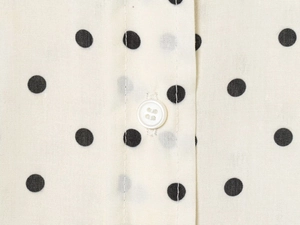 Detailed macro shot of vintage polka dot shirt fabric with white button and neat stitching