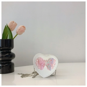 Detail of white heart-shaped girl's purse featuring sequin butterfly and silver chain