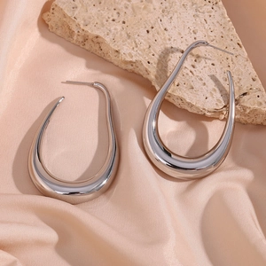 Close-up of silver hollow curved earrings on silk fabric with natural decorative stone
