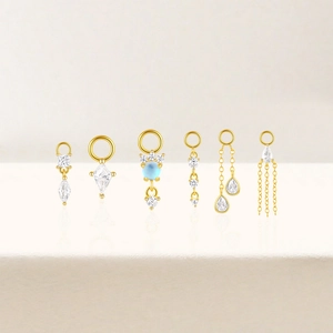 Macro view of six gold-plated S925 silver earring charms with zircons and blue stones