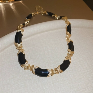 Vue détaillée du collier en émail noir avec maillons croisés en forme de X dorés torsadés
