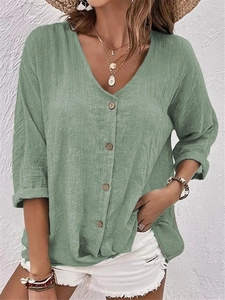 Détail de la blouse ample col en V vert sauge avec patte de boutonnage élégante