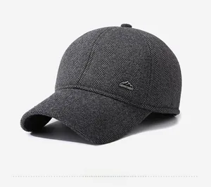 Detail of dark grey herringbone wool baseball cap featuring mountain logo metal badge