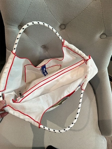 Interior detail of nylon tote bag showing zipper closure, inner pocket and red edge trim