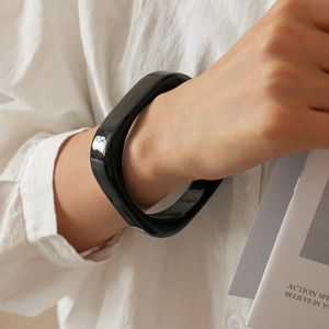 Polished black resin irregular square bangle styled with minimalist linen outfit