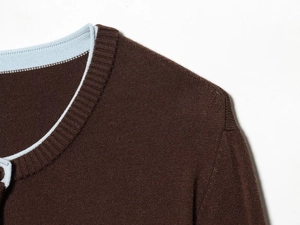 Detail of dark brown knit cardigan featuring light blue contrast neckline piping