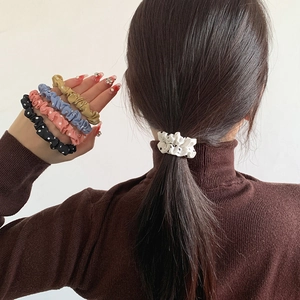 Detail showing five colorful polka dot scrunchies and white variant worn in a ponytail