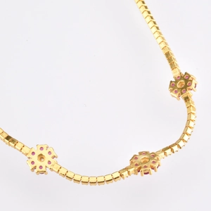 Detailed macro view of gold chain necklace with delicate pink zircon flower pendants