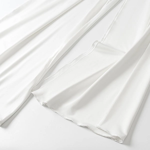 Detailed view of the pure white mesh hemline with fine stitching and flowing fabric drape
