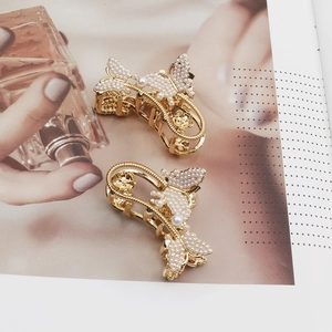 Elegante goldene Schmetterlings-Haarklammern mit Perlen und Strass auf Magazin-Hintergrund