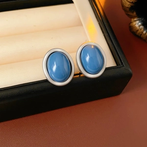 Close-up of blue oval earrings with silver borders displayed in a premium velvet jewelry box