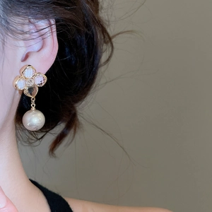 Close-up of elegant gold flower earrings with crystal petals and hanging pearl drops