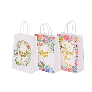 Three elegant white kraft paper gift bags featuring floral patterns and gold Thank You text