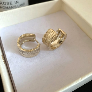 Detailed macro view of 18K gold plated striped hoop earrings in a jewelry box