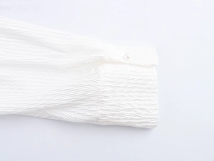 Close-up of white textured sleeve cuff featuring a single elegant pearl button detail