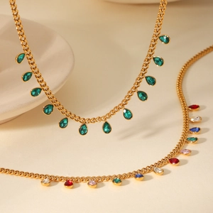 Detail of gold chain necklaces with green and colorful zircon teardrop pendants
