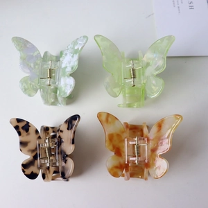 Top view of butterfly hair claws in acetate and colorful patterns on white surface