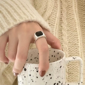 Close-up of S925 silver ring with square black agate on person wearing beige sweater