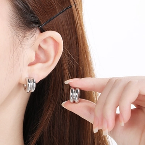Detail of silver double-hoop earrings in cylinder style on model and hand display