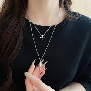 Minimalist double-layered silver cross necklace with unique lava texture on a black top