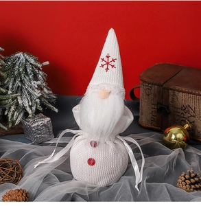 Detailed view of a white knitted Christmas gnome featuring red snowflake embroidery and fur beard